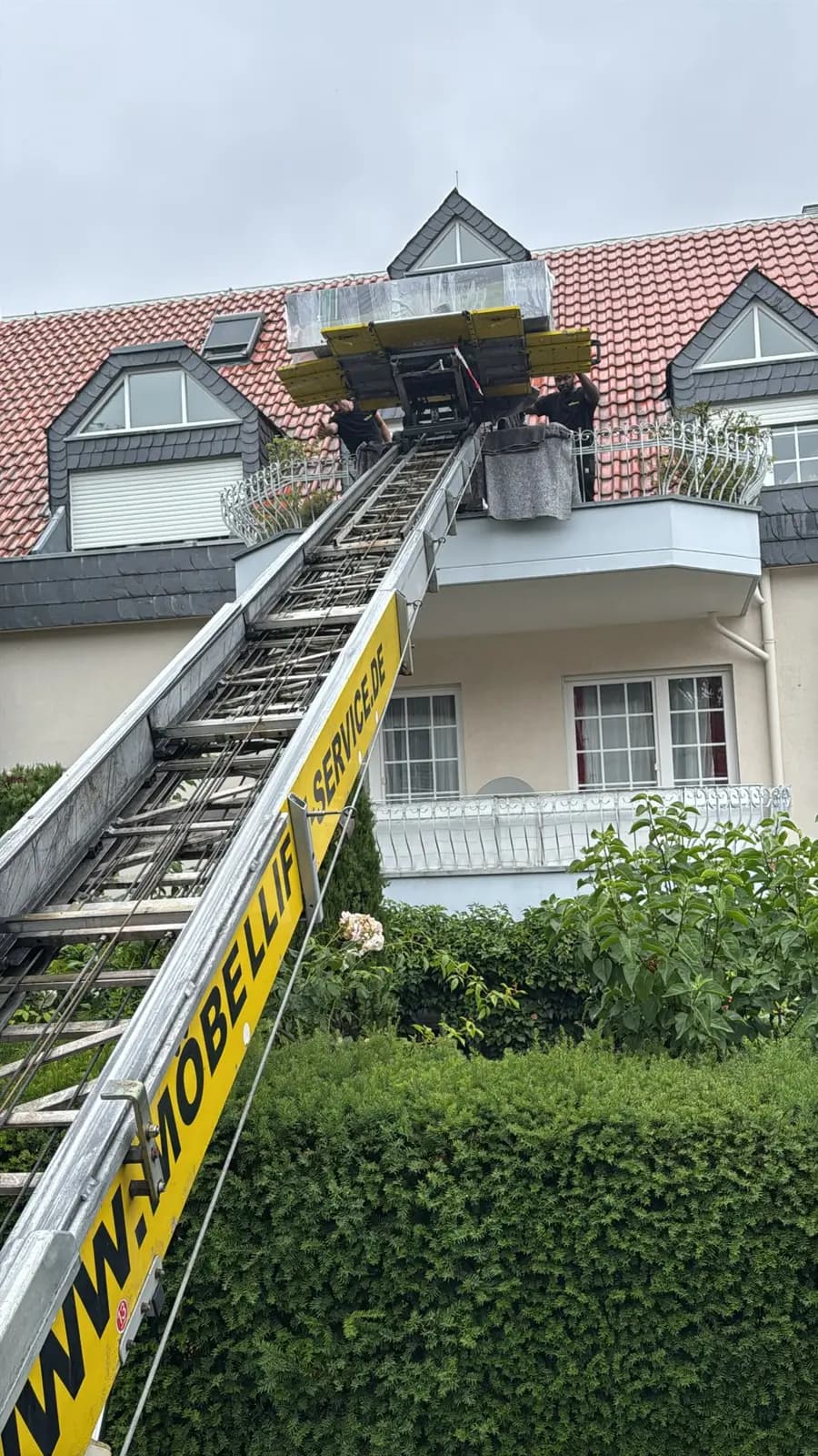 Vollständig ausgefahrener Möbellift von Family Umzüge reicht bis zum Dachgeschoss eines Mehrfamilienhauses
