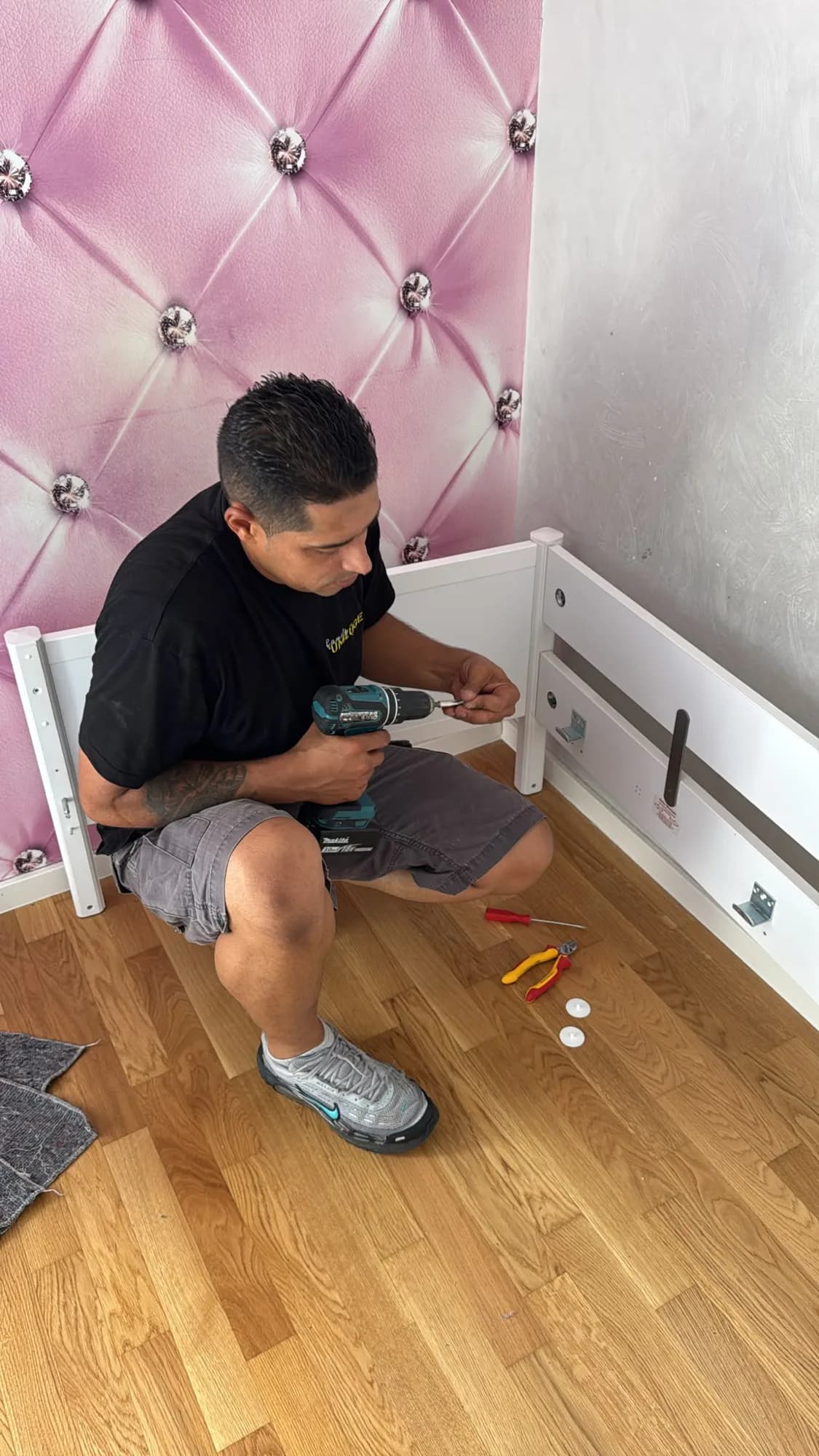 Mitarbeiter von Family Umzüge baut ein weißes Kinderbett im Kinderzimmer auf