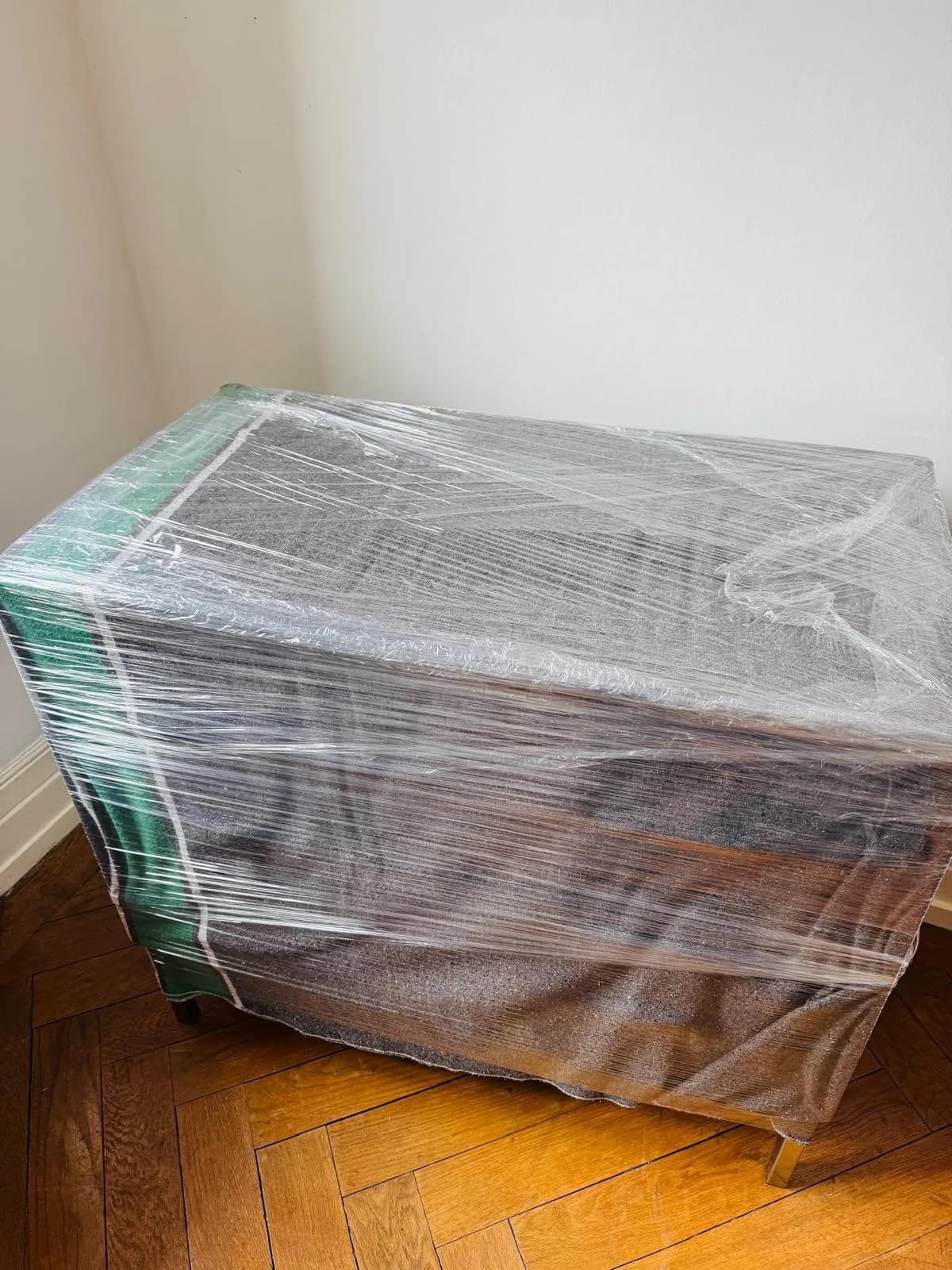 Kommode erst mit Umzugsdecke abgedeckt und dann mit Stretchfolie umwickelt, transportfertig auf dem Parkett