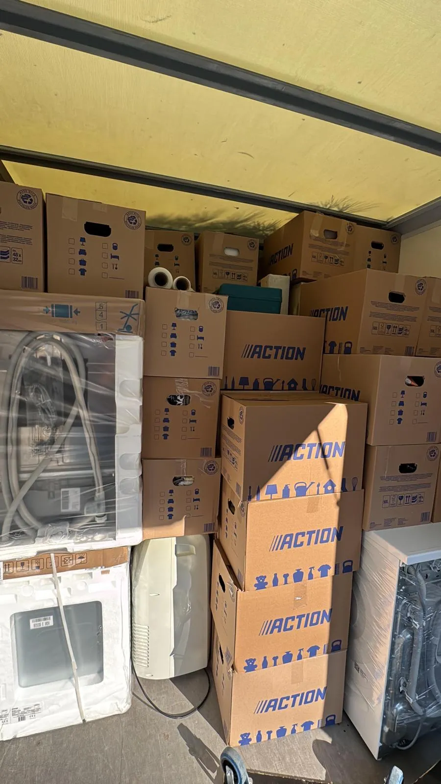 Umzugs-Lkw von innen: dicht gestapelte Umzugskartons, dazwischen Waschmaschine und Herd in Stretchfolie gesichert