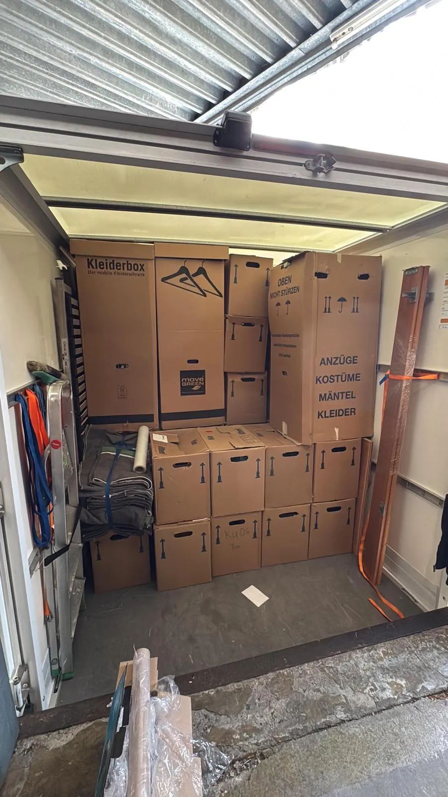 Kofferaufbau eines Umzugswagens mit Kleiderboxen, gestapelten Umzugskartons, Umzugsdecken und Spanngurten zur Sicherung
