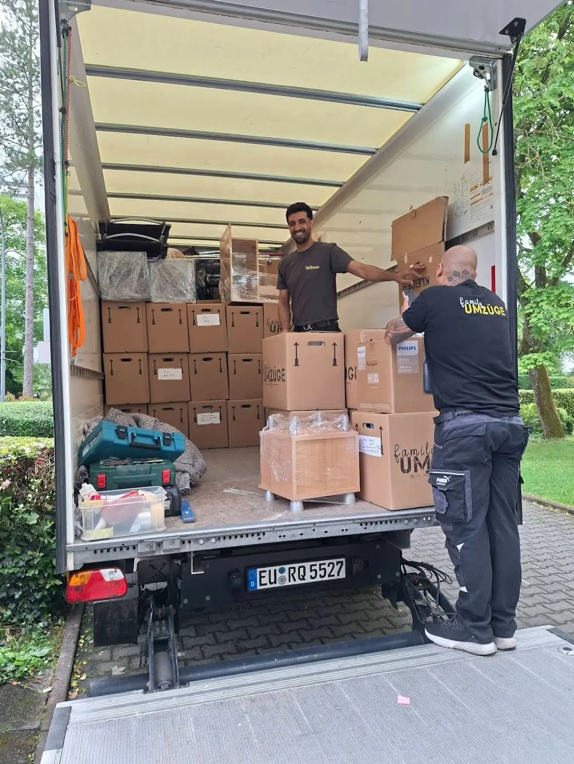 Zwei Mitarbeiter von Family Umzüge beladen einen Umzugs-Lkw mit beschrifteten Kartons in Frankfurt