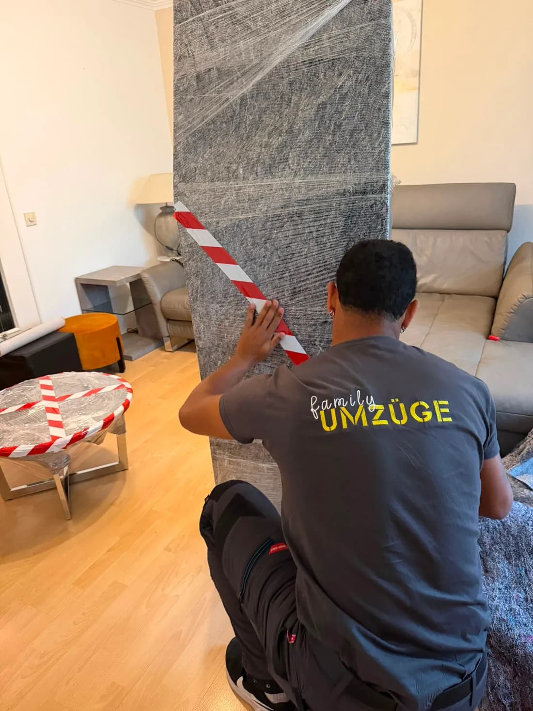 Mitarbeiter von Family Umzüge verpackt ein Möbelstück sorgfältig mit Decke und Warnband