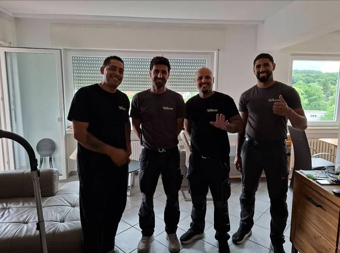 Das vierköpfige Team von Family Umzüge lächelt in einer hellen Kundenwohnung in Frankfurt